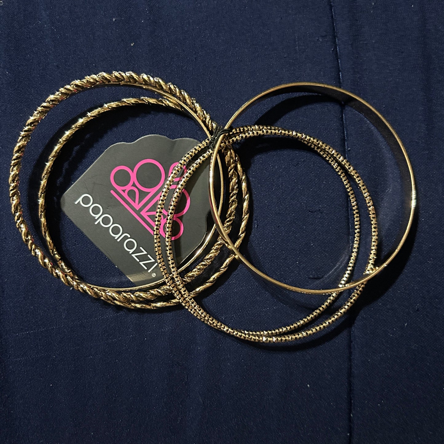 Gold hoop earrings on a dark blue surface with a visible brand logo.