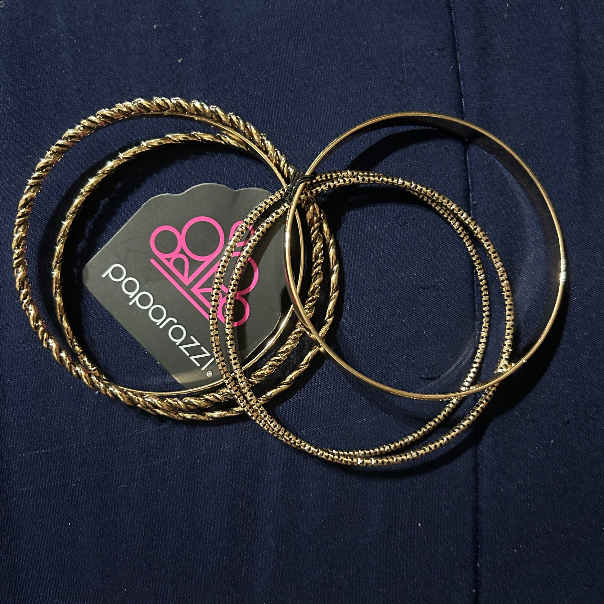 Gold hoop earrings on a dark blue surface with a visible brand logo.